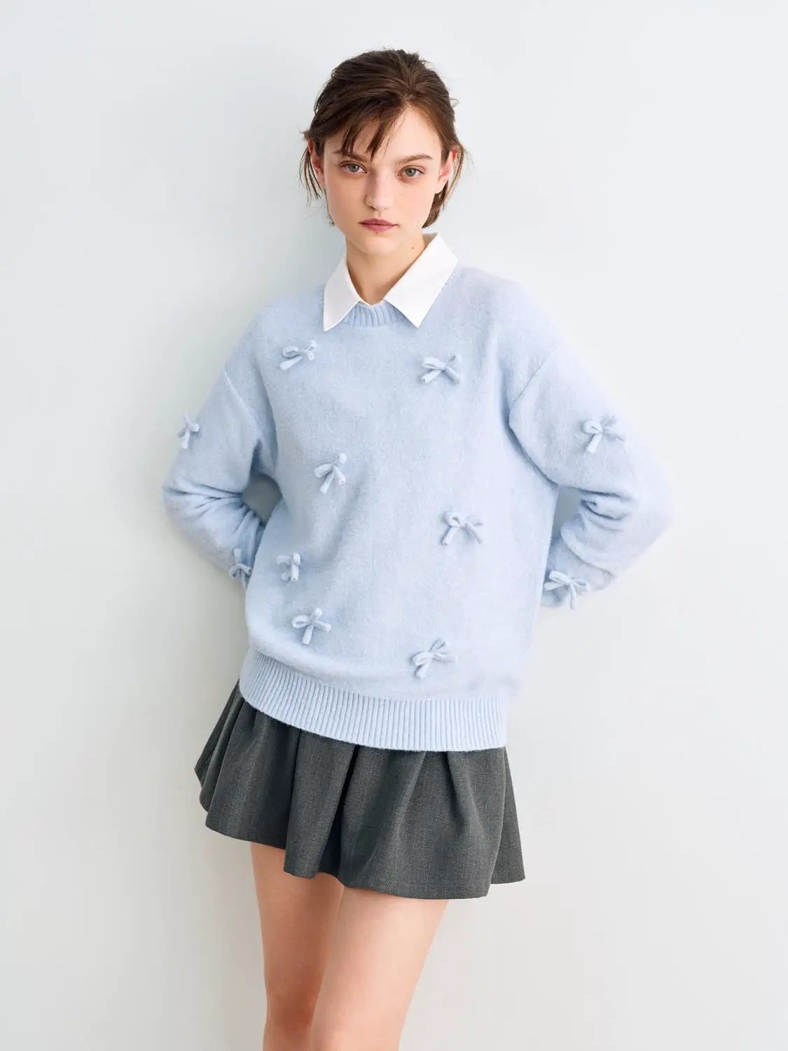 Knit T-Shirt; light blue knit top with bow appliques, worn over a white collared shirt and a gray pleated skirt.
