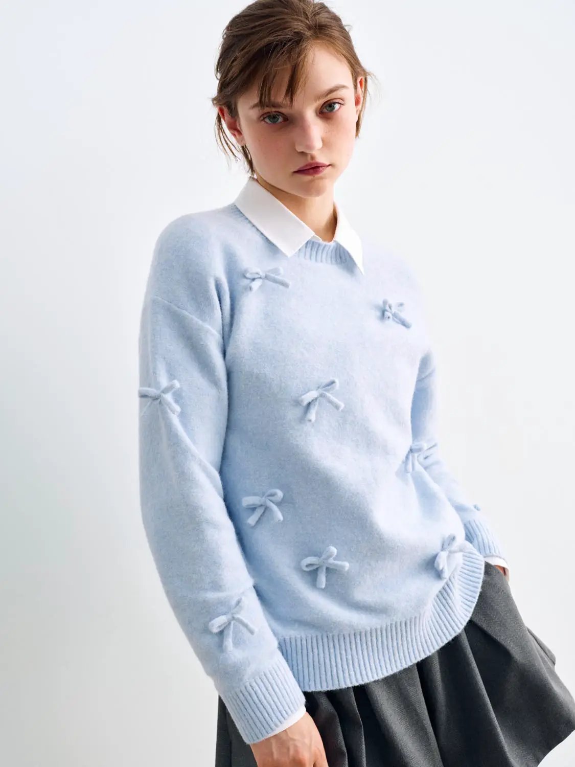 Knit T-Shirt in light blue with bow embellishments; worn over a white collared shirt.