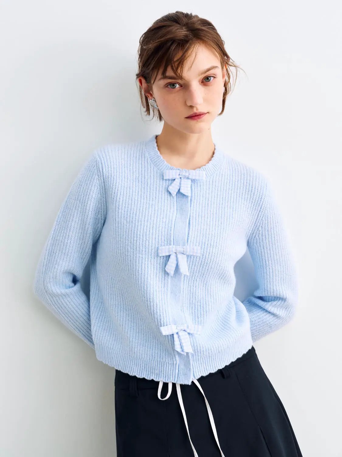 Knitted cardigan in light blue with bow accents along front.