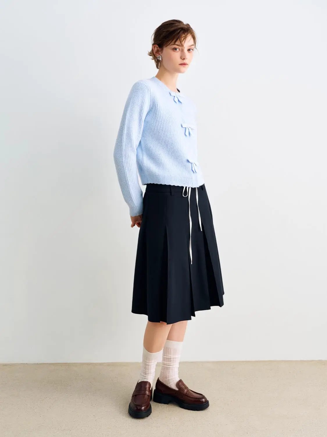 Knitted cardigan by Urban Revivo Fashion in light blue, cropped fit with front ribbon bows on model.
