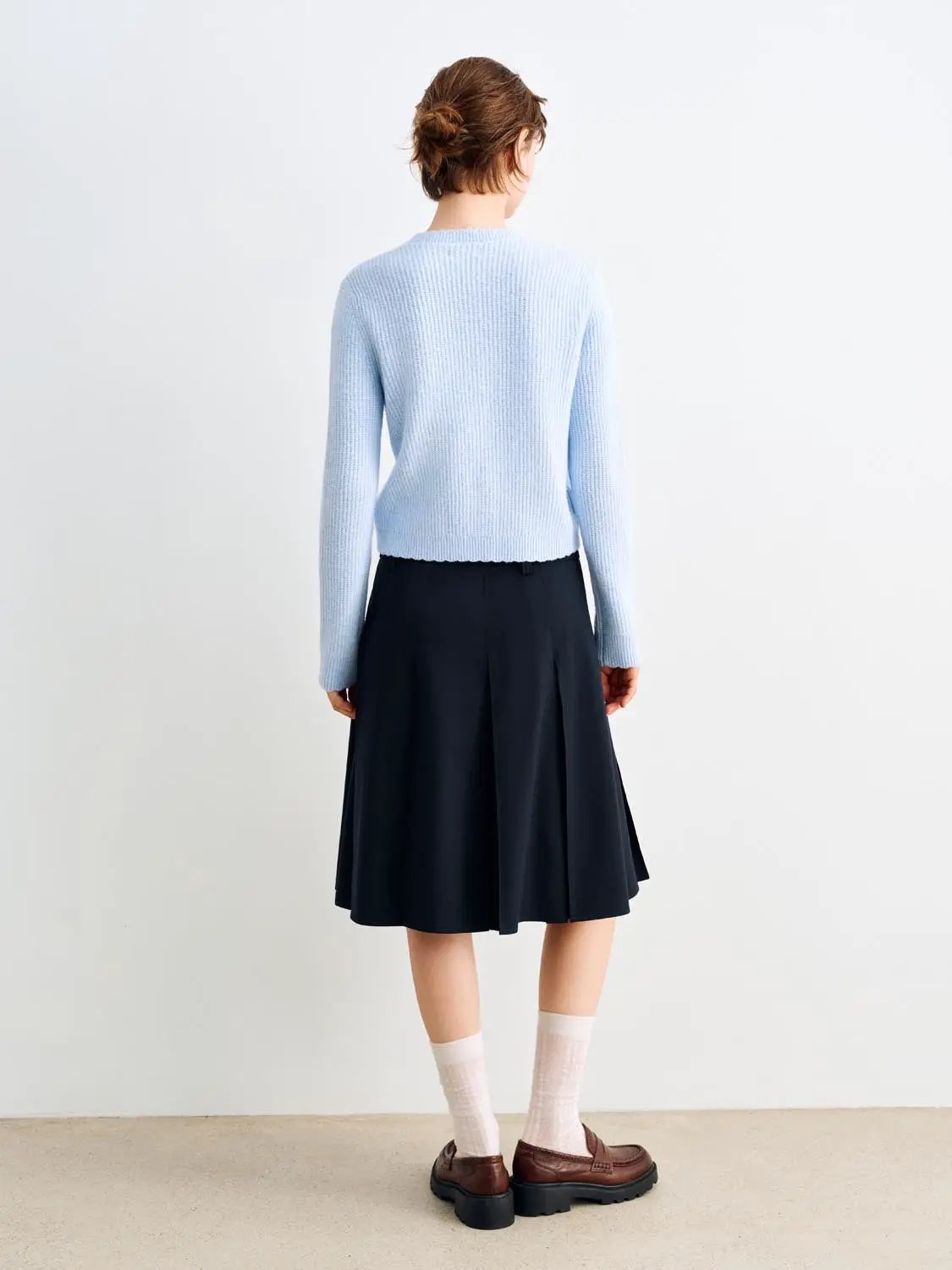 Knitted cardigan in light blue, back view on a model.