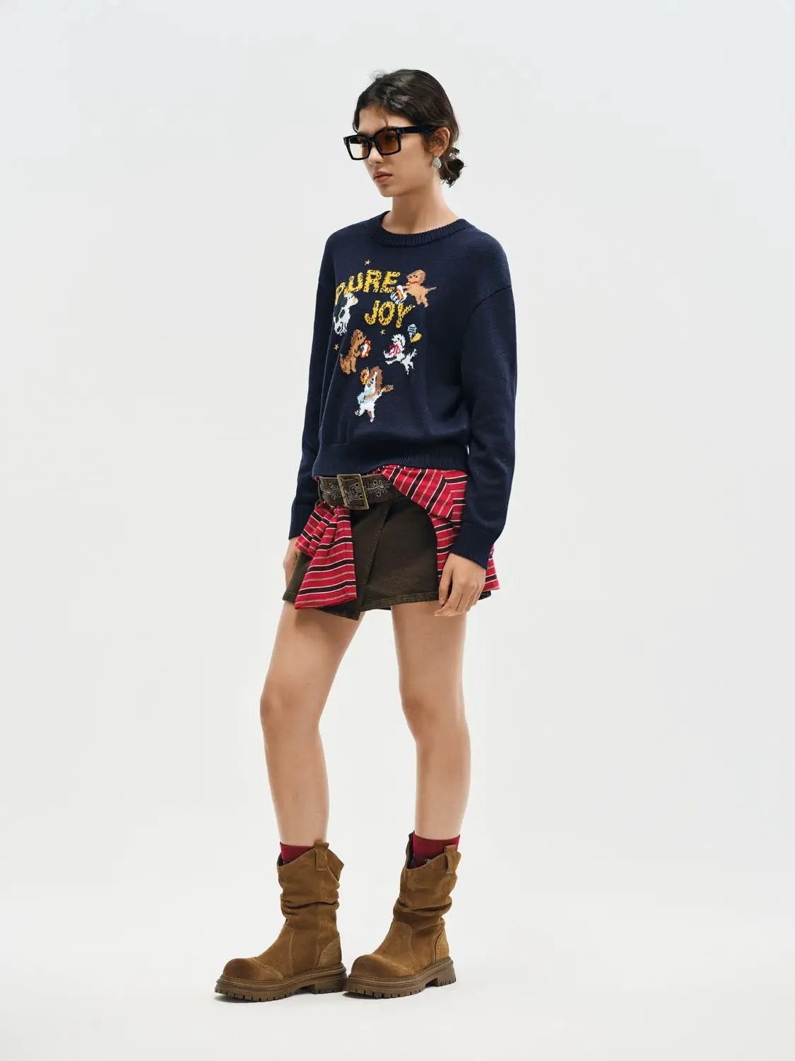 Knitted T-shirt navy sweater with colorful graphic motif PURE JOY, tied at waist red plaid shirt and brown boots.