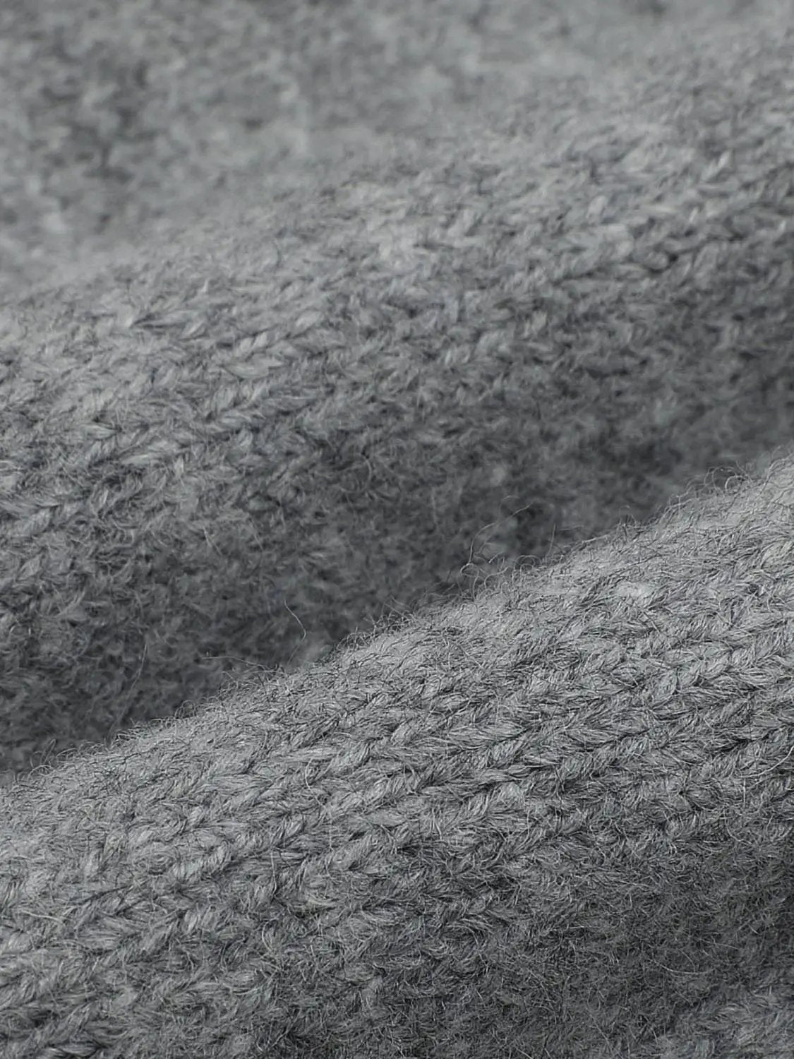 Knitwear T-shirt fabric close-up in grey, showing textured knitted fibers