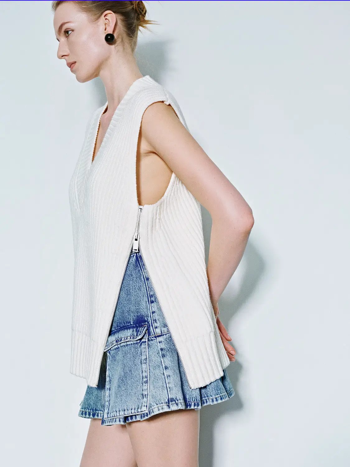 Loose V-Neck Knitted Vest in white with side zipper, worn with a denim mini skirt