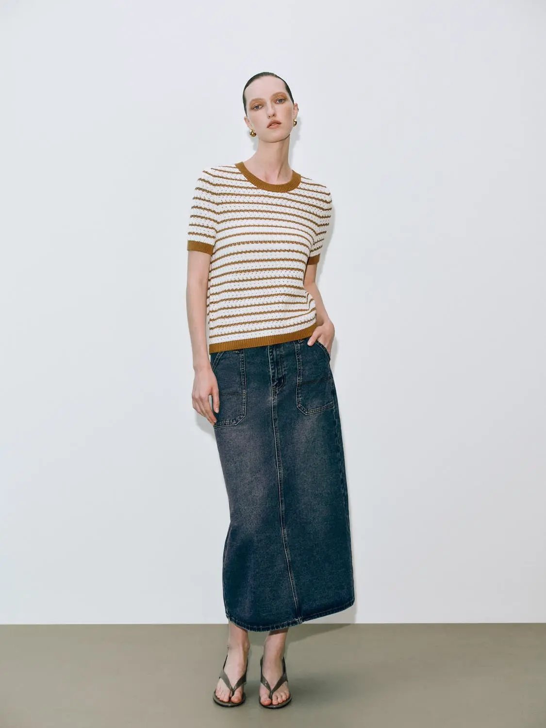 Round neck striped knit short-sleeve cotton T-shirt in white with brown stripes, paired with a dark denim midi skirt.