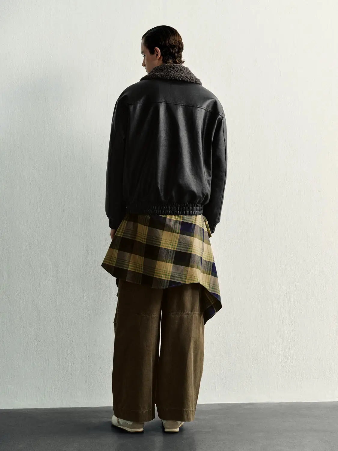 Padded Jacket in black faux leather with shearling collar and elastic hem.
