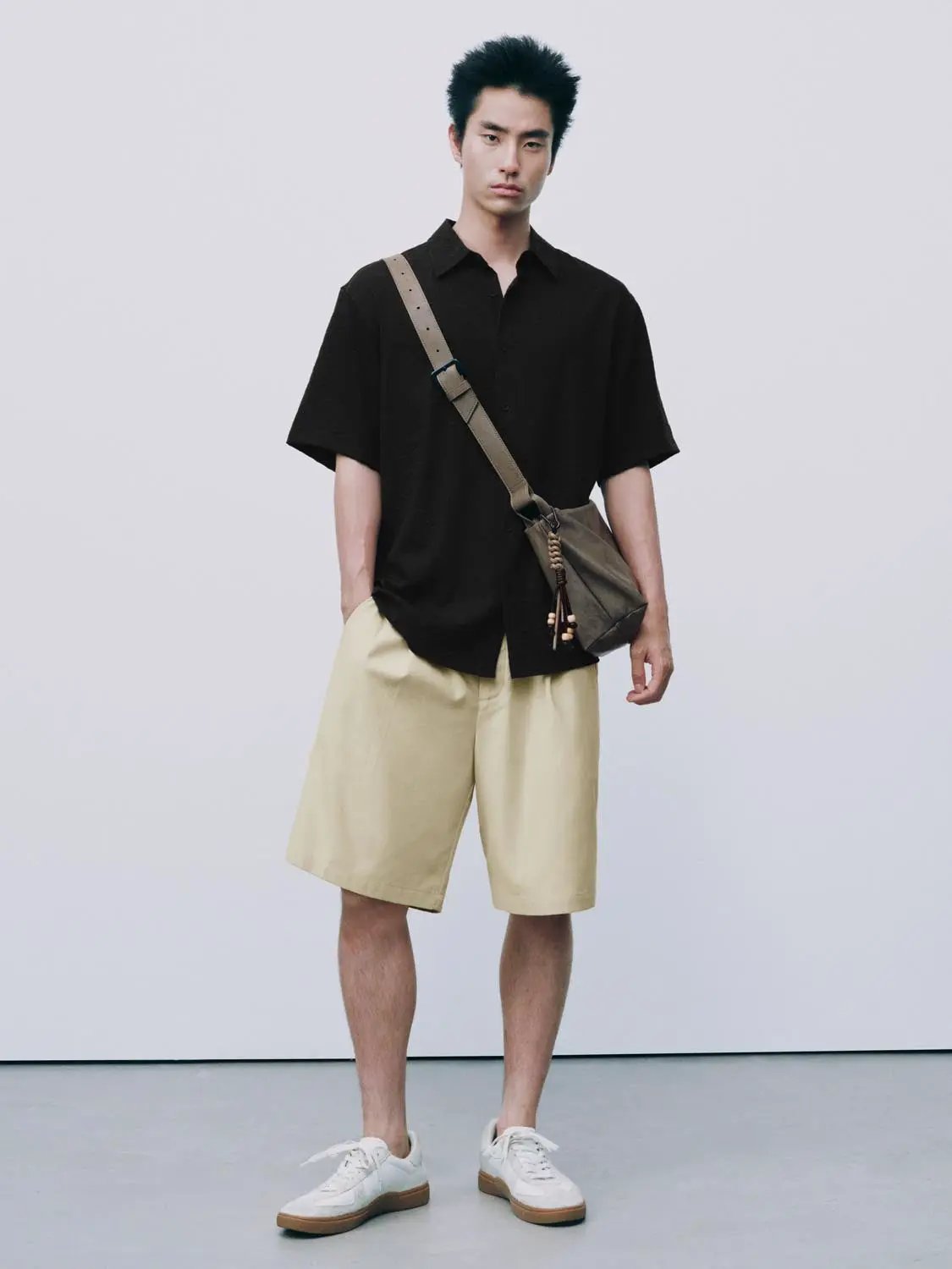 Open-Front Shirt; black short-sleeve men's shirt shown with beige shorts and a tan crossbody bag.