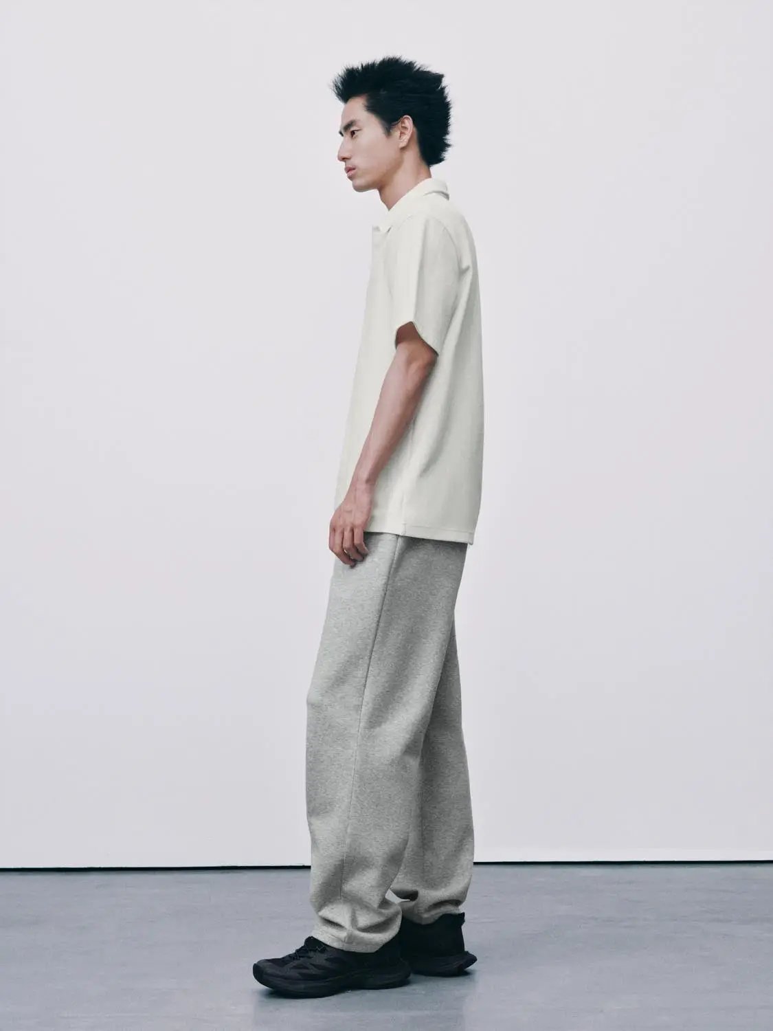 Textured brushed polo cotton-blend shirt in cream on a male model, paired with gray sweatpants and black sneakers.
