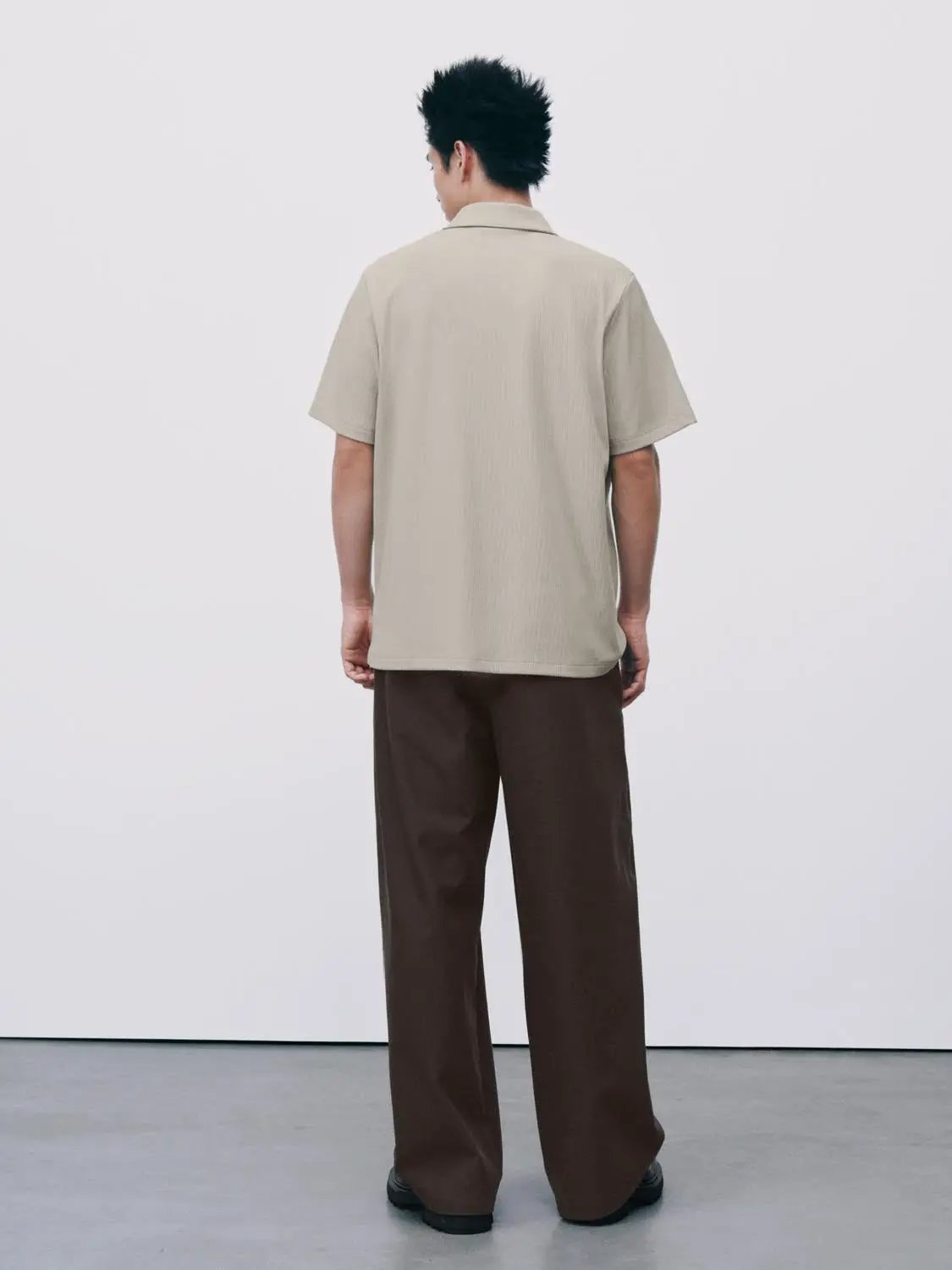 Beige polo shirt, short-sleeve with collar, back view on model.