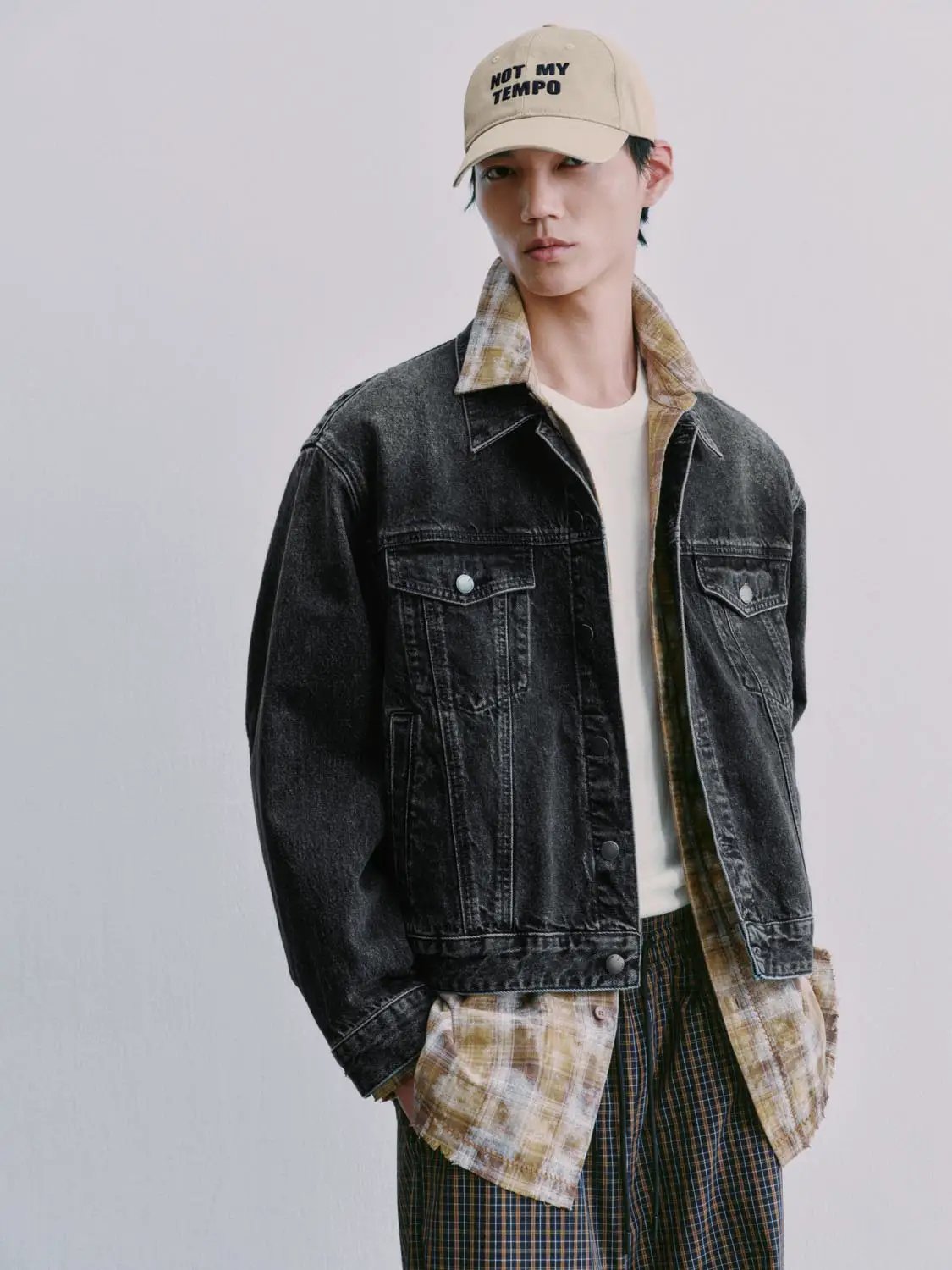Denim jacket in dark wash with beige plaid shirt visible underneath