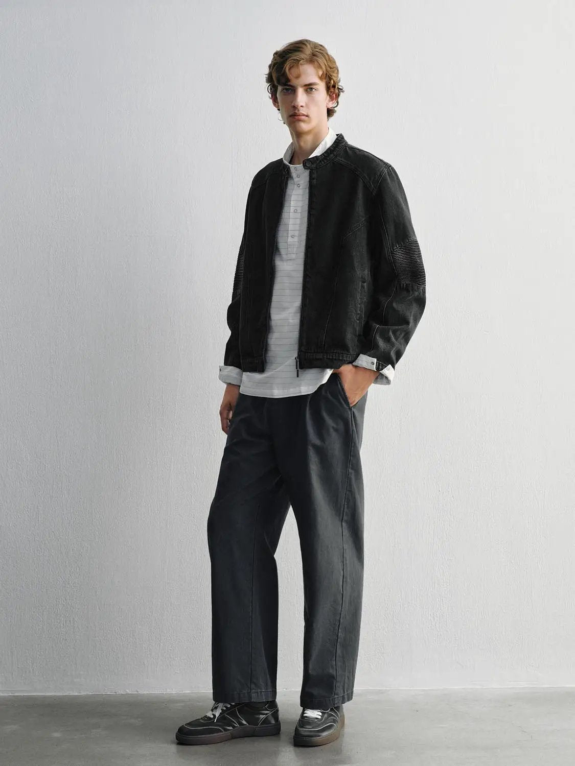 Black denim jacket worn by a male model over a light gray striped shirt.
