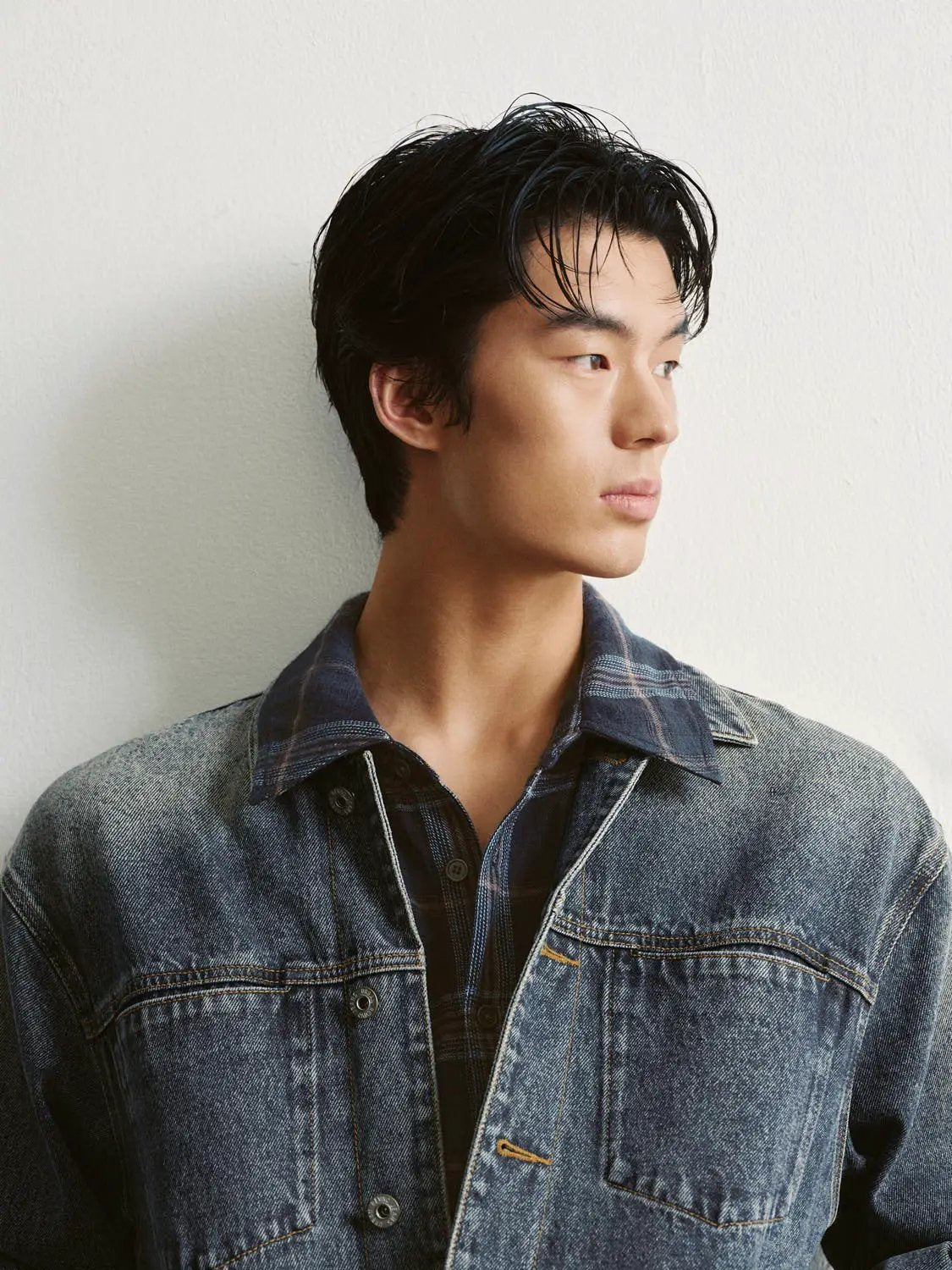 Faded blue denim jacket worn over a plaid shirt on a man.