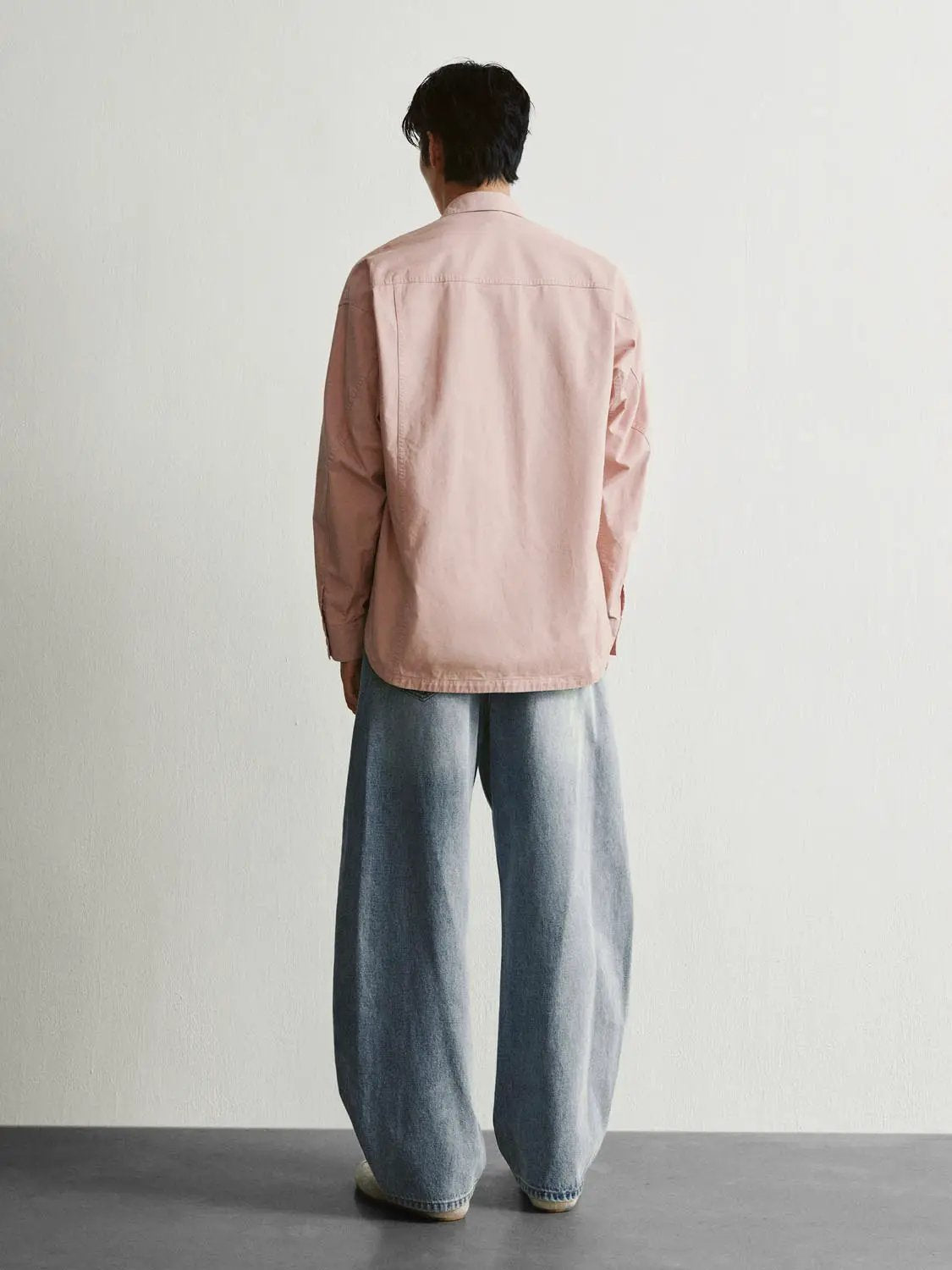 Button-front shirt in soft pink, back view paired with wide-leg blue jeans