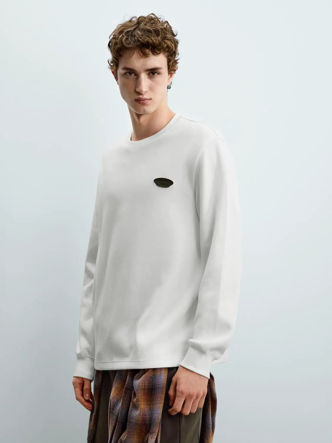 Sweatshirt in white with a small oval chest logo patch; long sleeves.