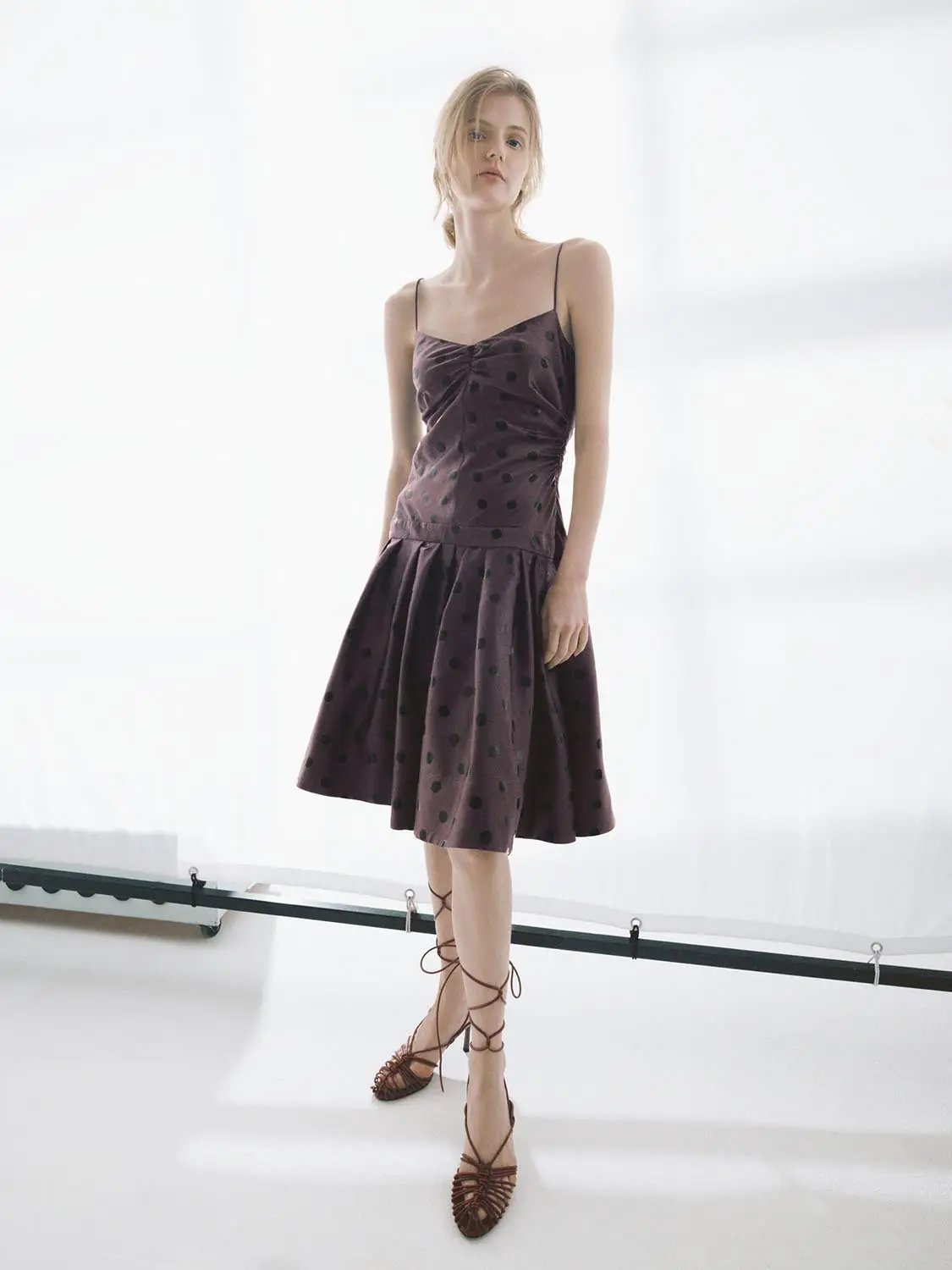 A-line dress in plum with black polka dots; spaghetti straps and knee-length satin-like fabric.