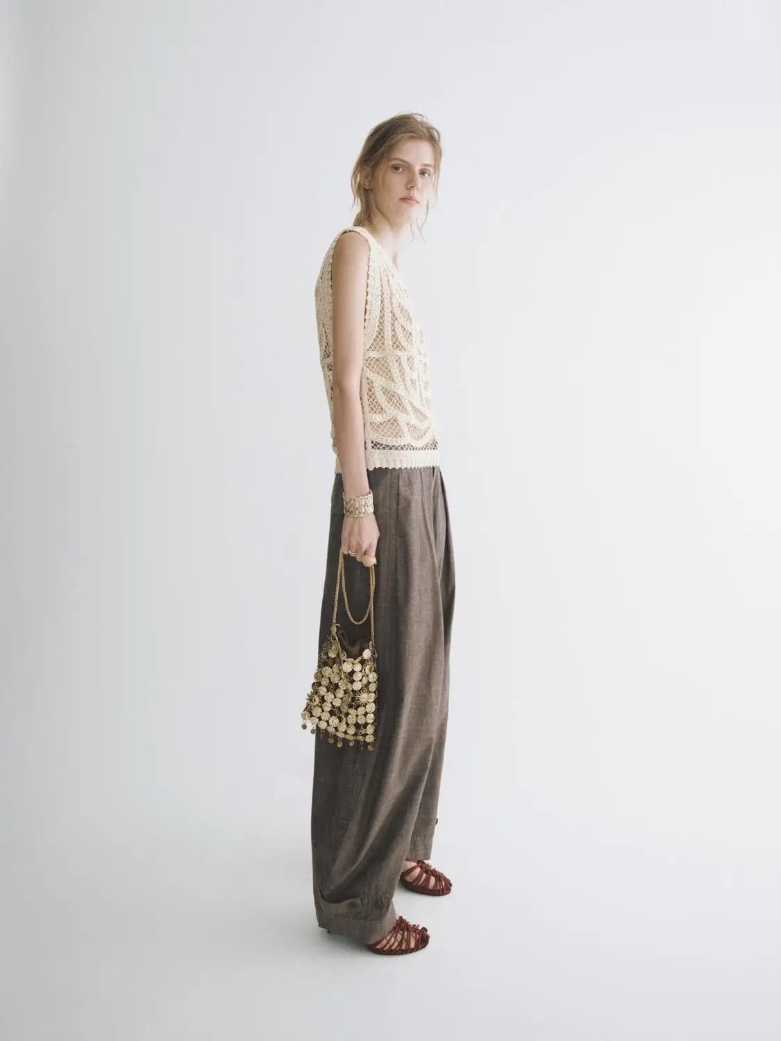 Textured openwork crochet knit cotton T-shirt, cream color, worn by a model with brown wide-leg trousers.