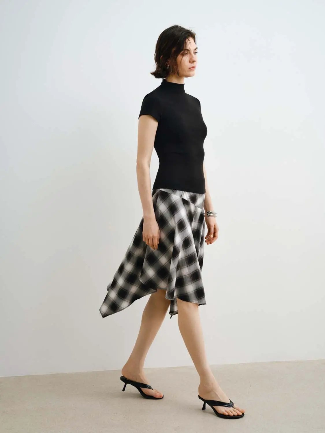 Women's modal-knit T-shirt with smooth finish in black; paired with a black-and-white plaid midi skirt.