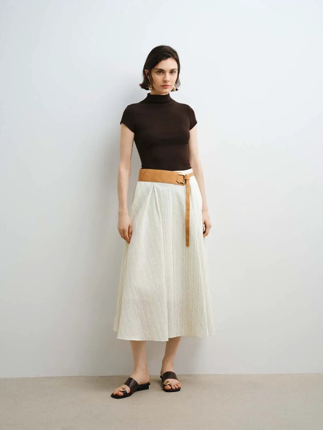 W_T-shirts: black modal-knit short-sleeve top with smooth finish, paired with white midi skirt and tan belt.