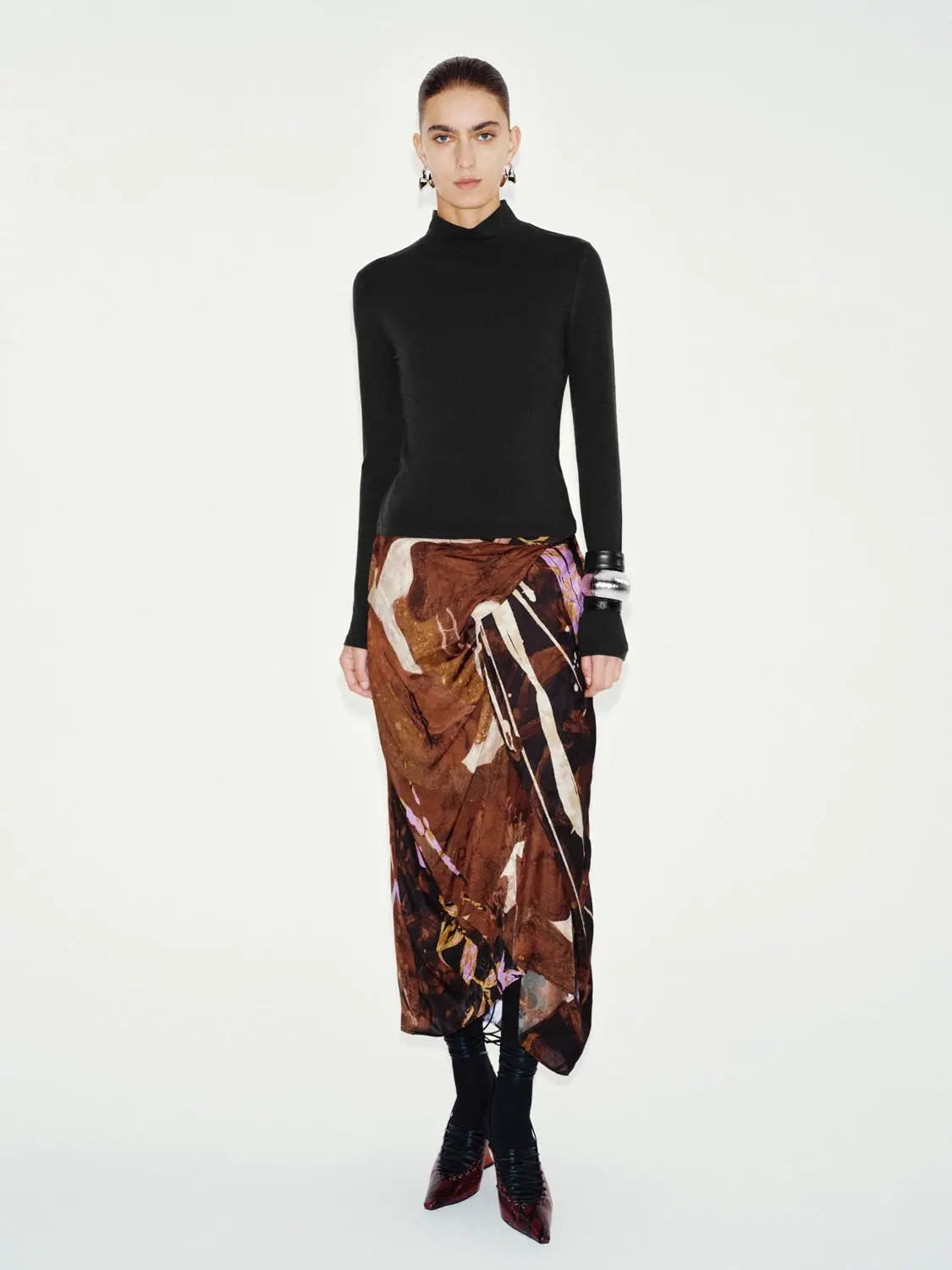 T-Shirt black long-sleeve top on model paired with a brown abstract-print skirt; stylish two-piece outfit.
