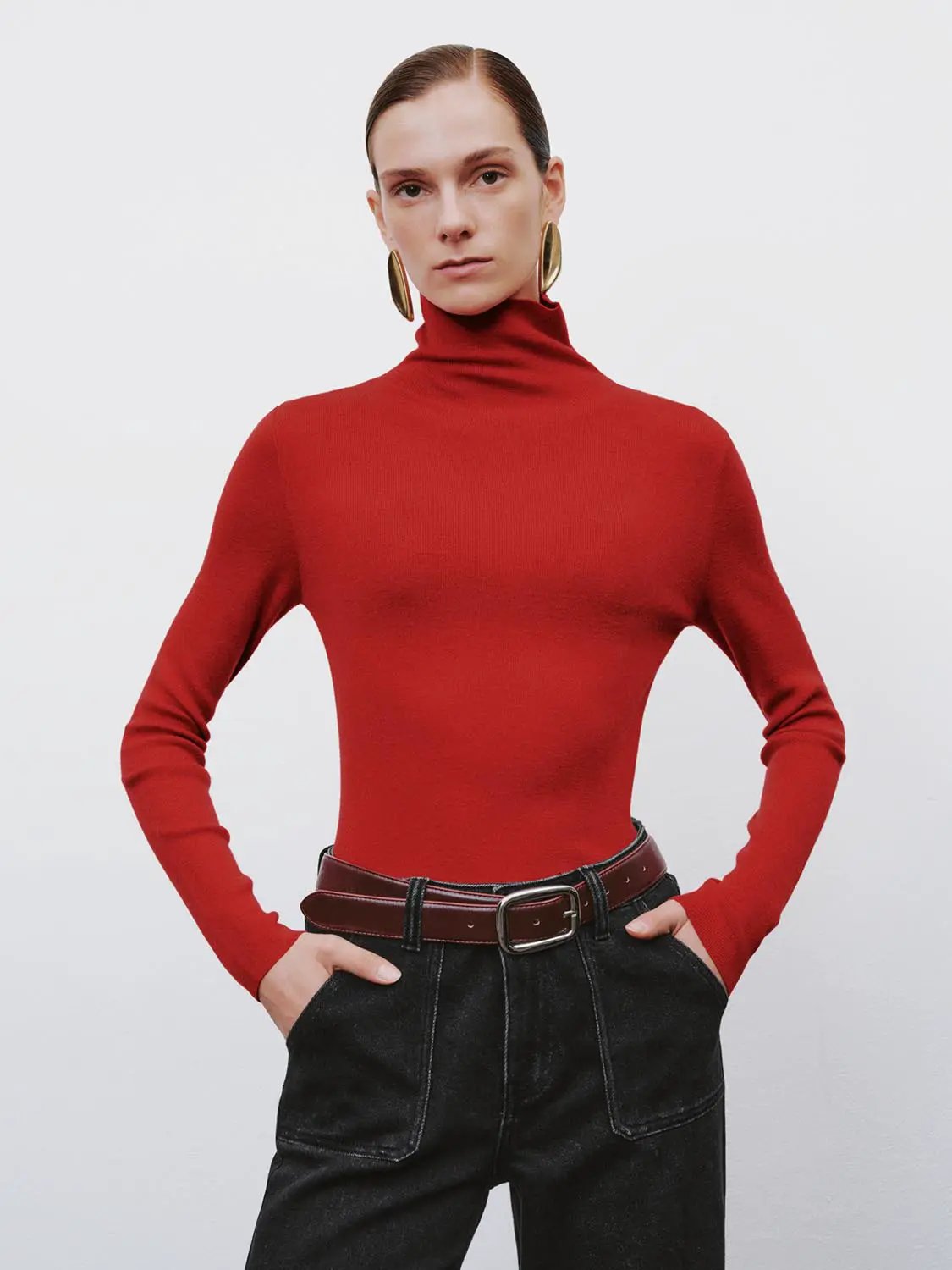 Ribbed fitted mock-neck long-sleeve sweater in red, shown with black denim and a brown belt.
