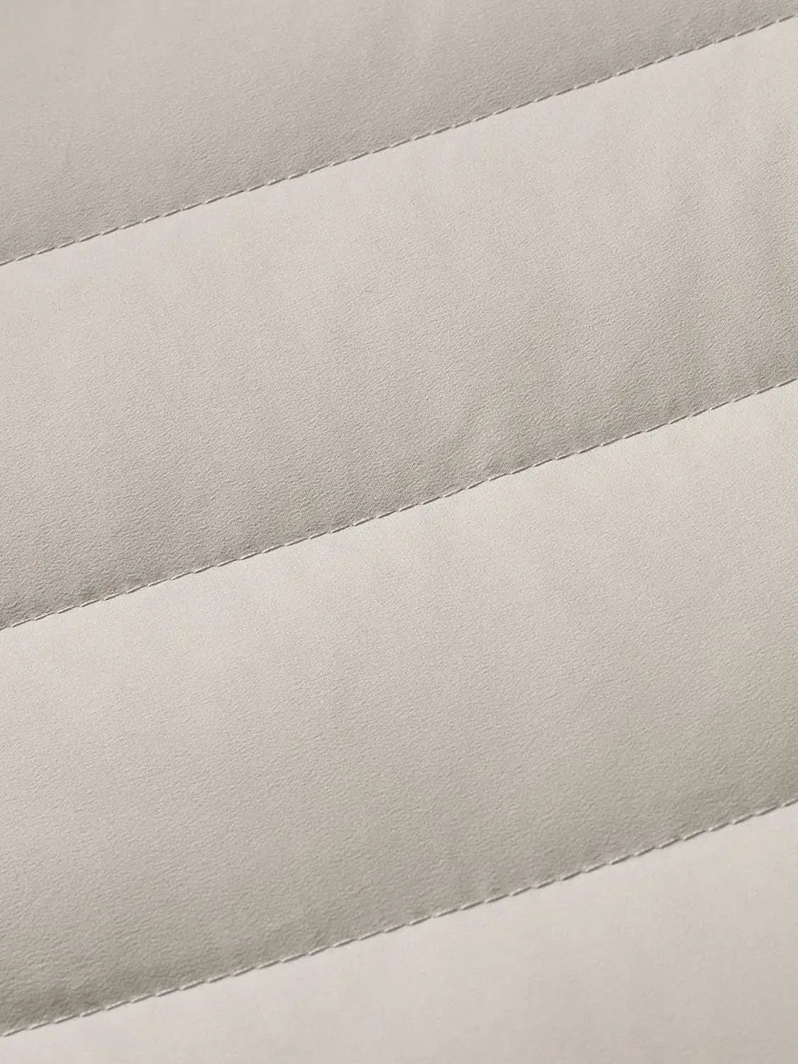 Down jacket fabric close-up in beige quilted stripes.