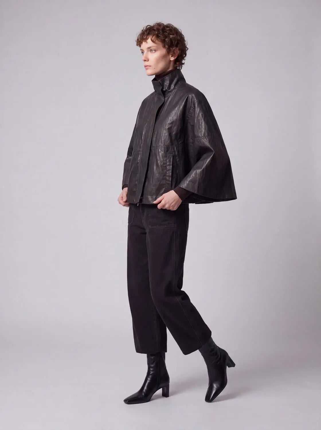 Cape poncho in black leather with a high stand collar and oversized cape silhouette