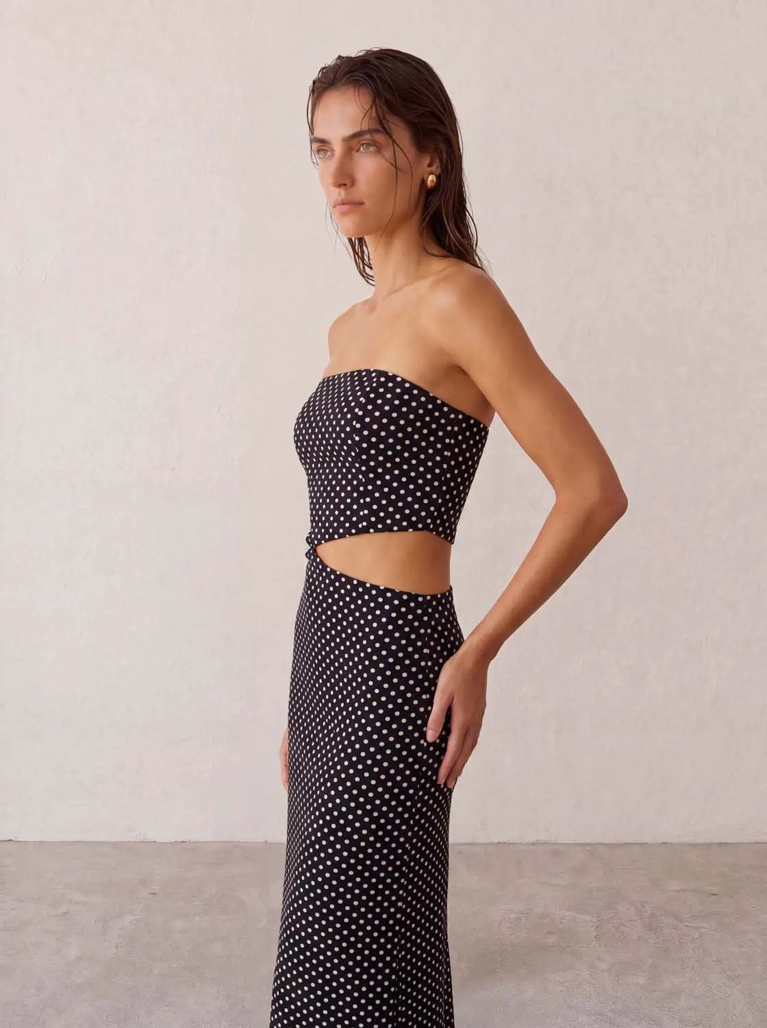 Skinny-fit dress in black with white polka dots, strapless bodice and waist cut-out