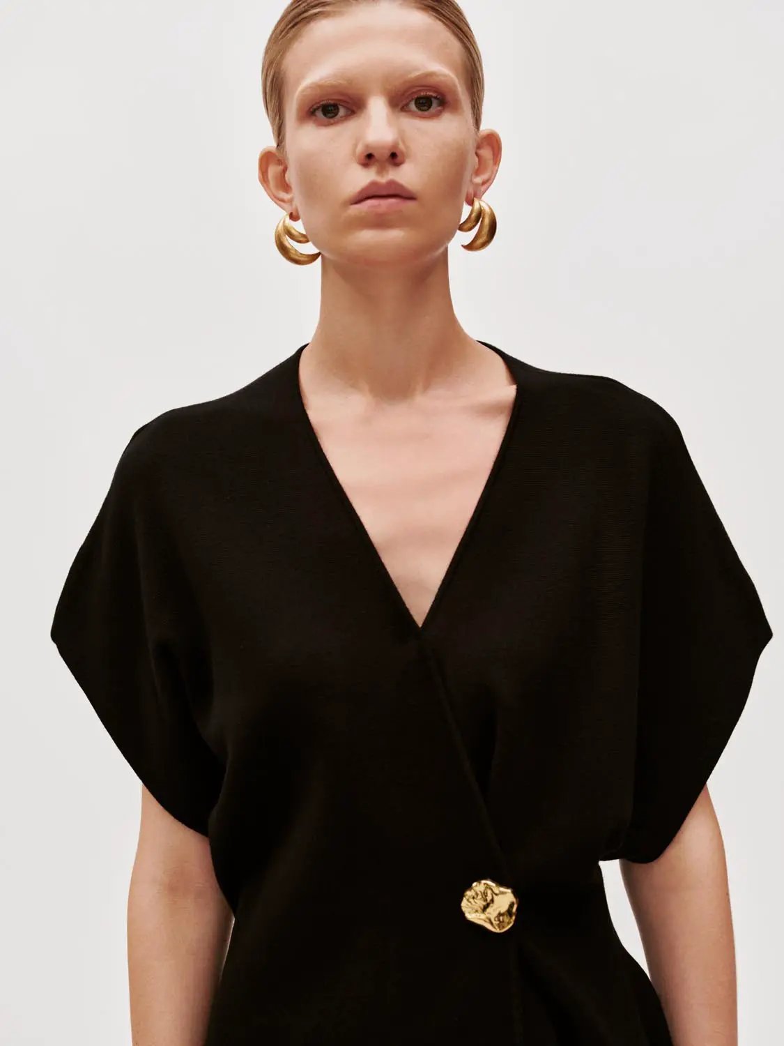 Wrap V-neck batwing short-sleeve knitted cardigan in black with gold-toned button detail.