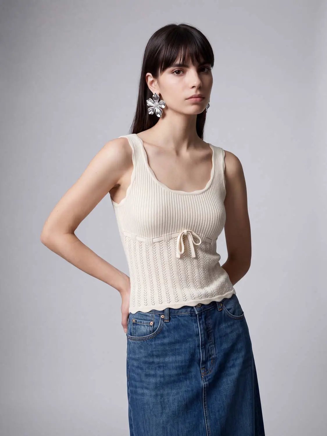 Knit T-shirt in cream ribbed knit with drawstring waist, sleeveless, paired with a blue denim skirt.