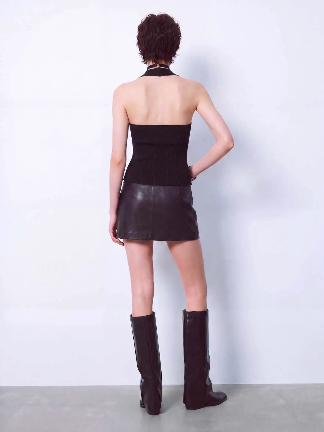Knitted T-Shirts black halter-neck top; black leather mini skirt and knee-high boots (three-piece outfit)