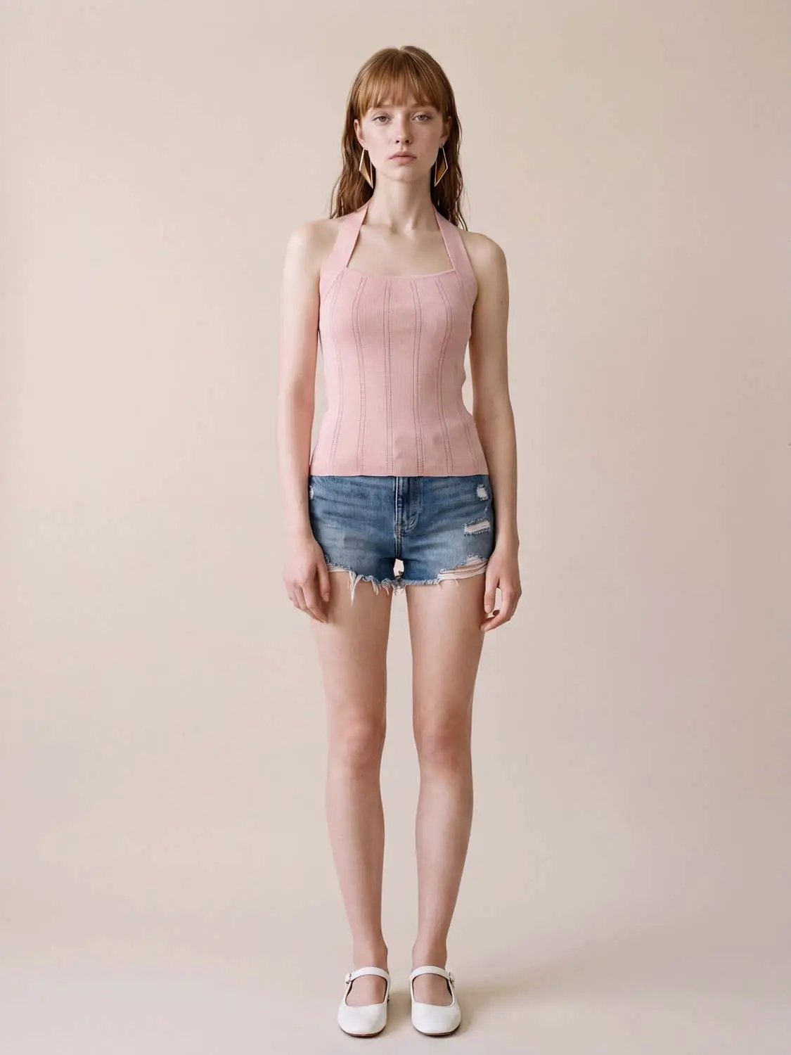 Knitted T-shirts pink ribbed halter top worn by a model with distressed denim shorts