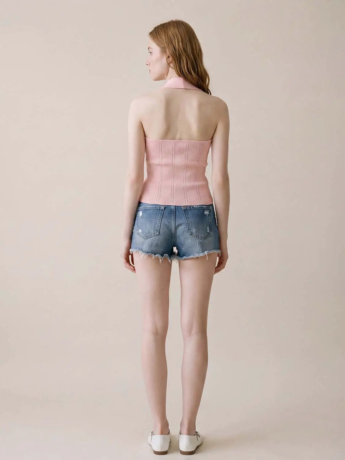 Knitted pink halter top, back view, with vertical ribbing; paired with frayed denim shorts.