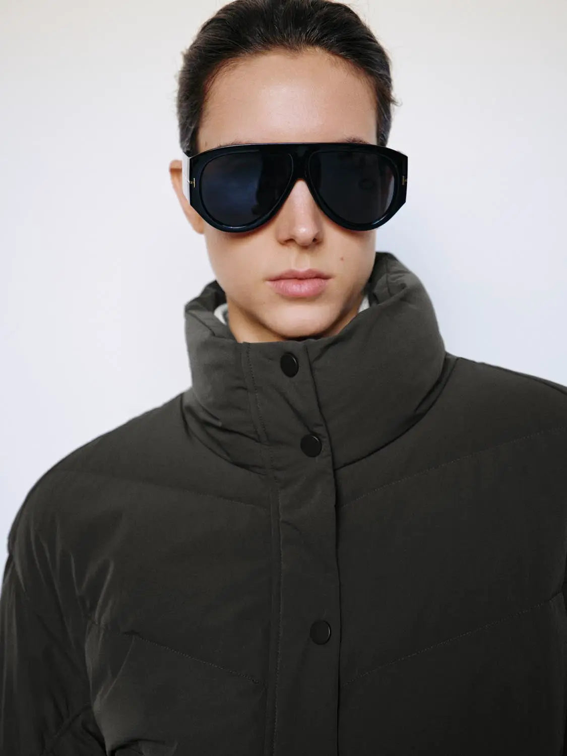 Down jacket in dark olive with stand collar, quilted puffer design and black snap buttons
