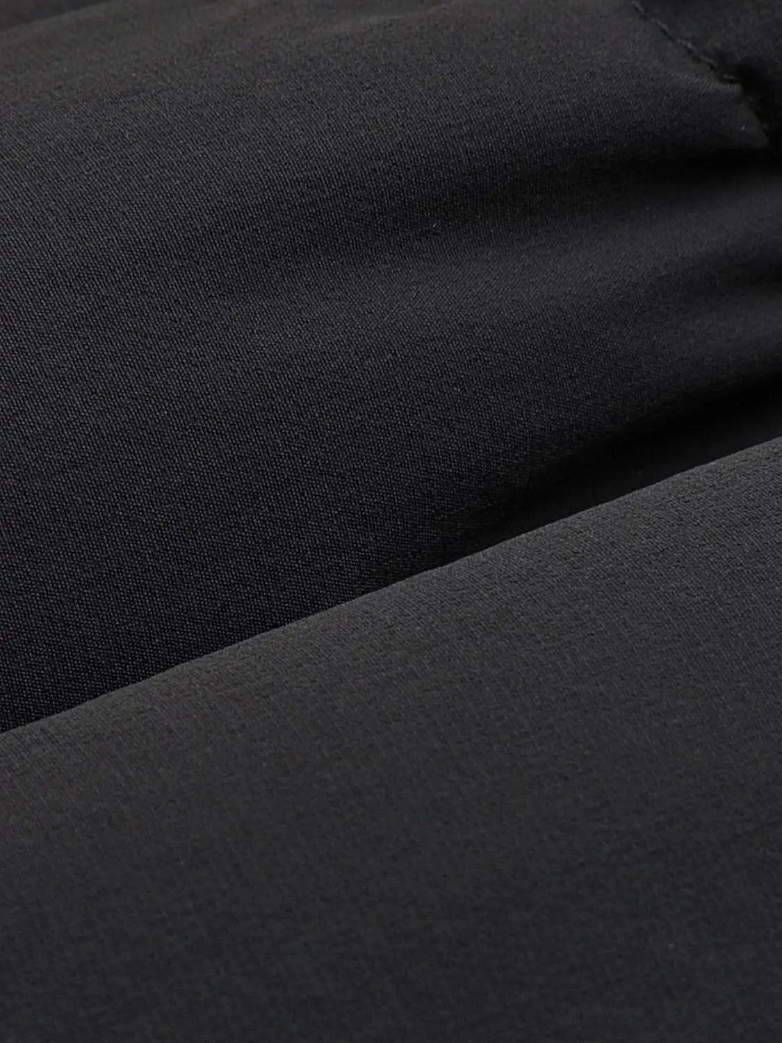 Down jacket fabric close-up in black with smooth matte texture.