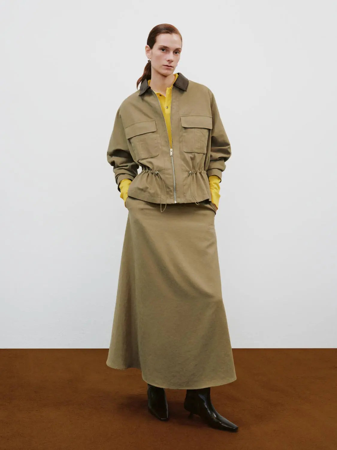 Padded Jacket(UR) in khaki with brown collar, front zip, two large flap pockets, and adjustable drawstring waist.