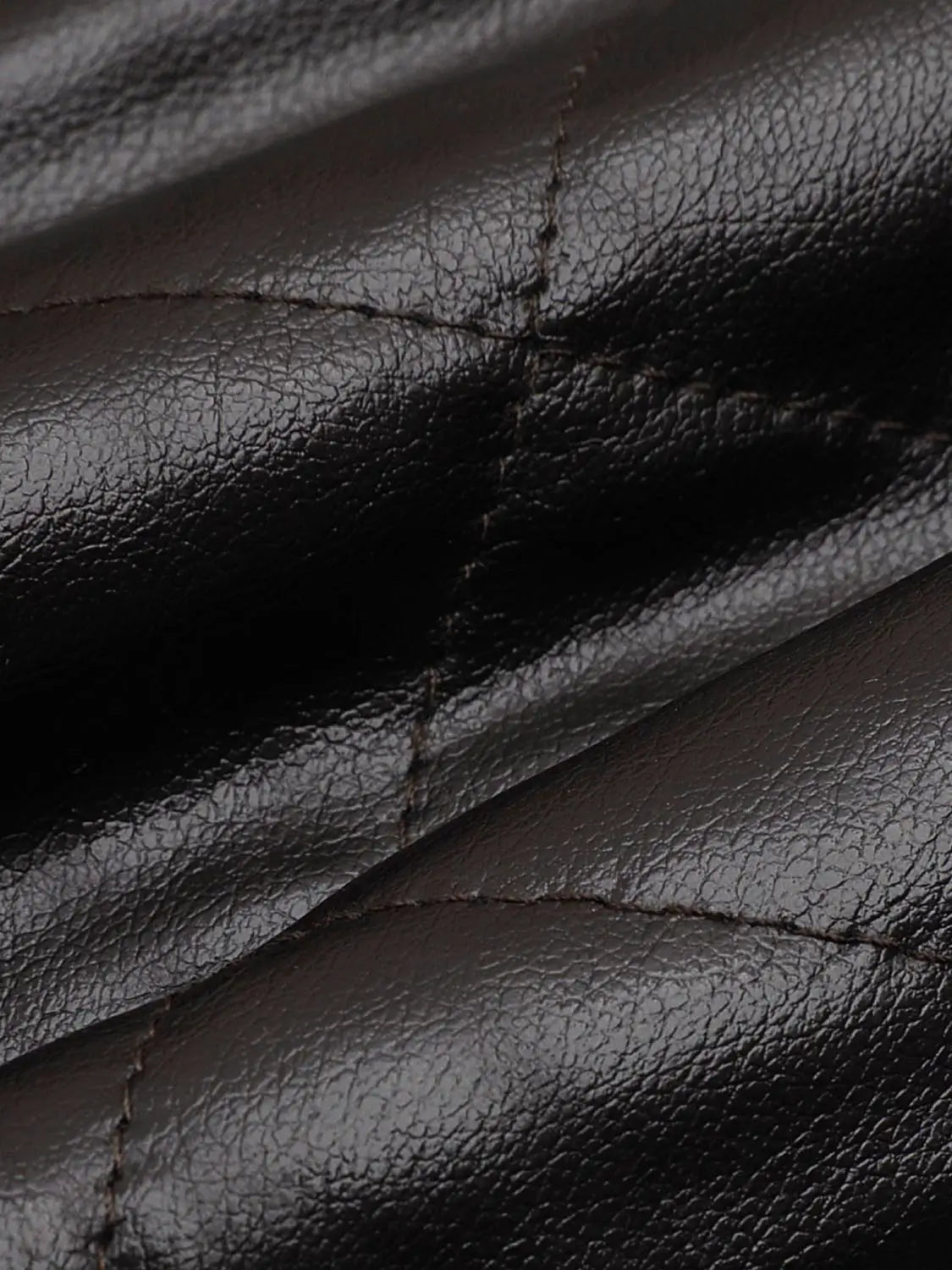 Padded jacket close-up in black leather-like material with brown stitching.