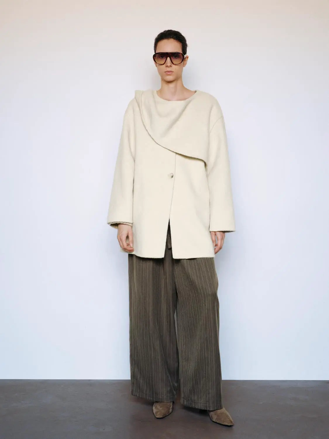 Coat in cream wool with an oversized draped collar and single-button closure.