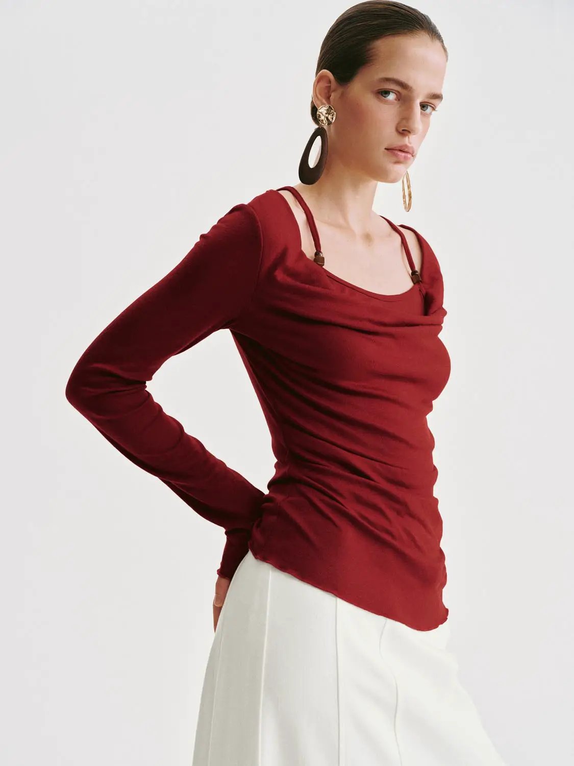 T-Shirt red long-sleeve ruched top with double-strap shoulders, worn with white skirt.