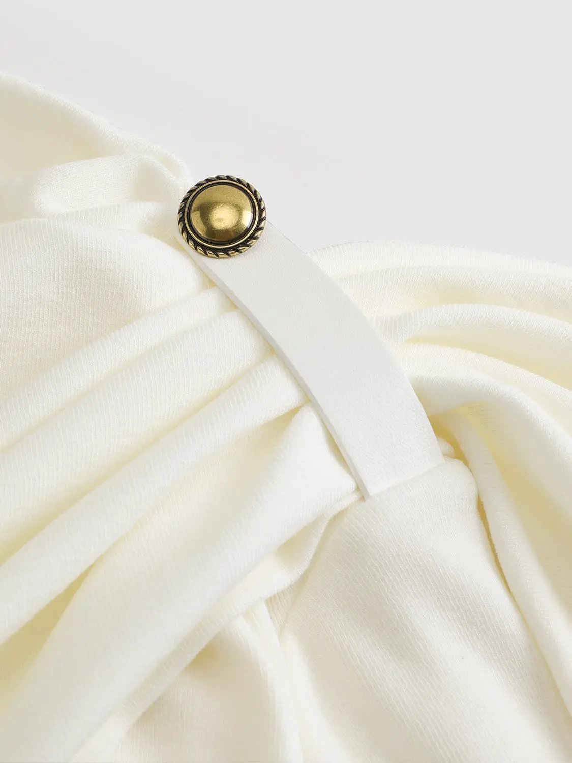 Draped one-shoulder long sleeve blouse in white fabric with gold button accent