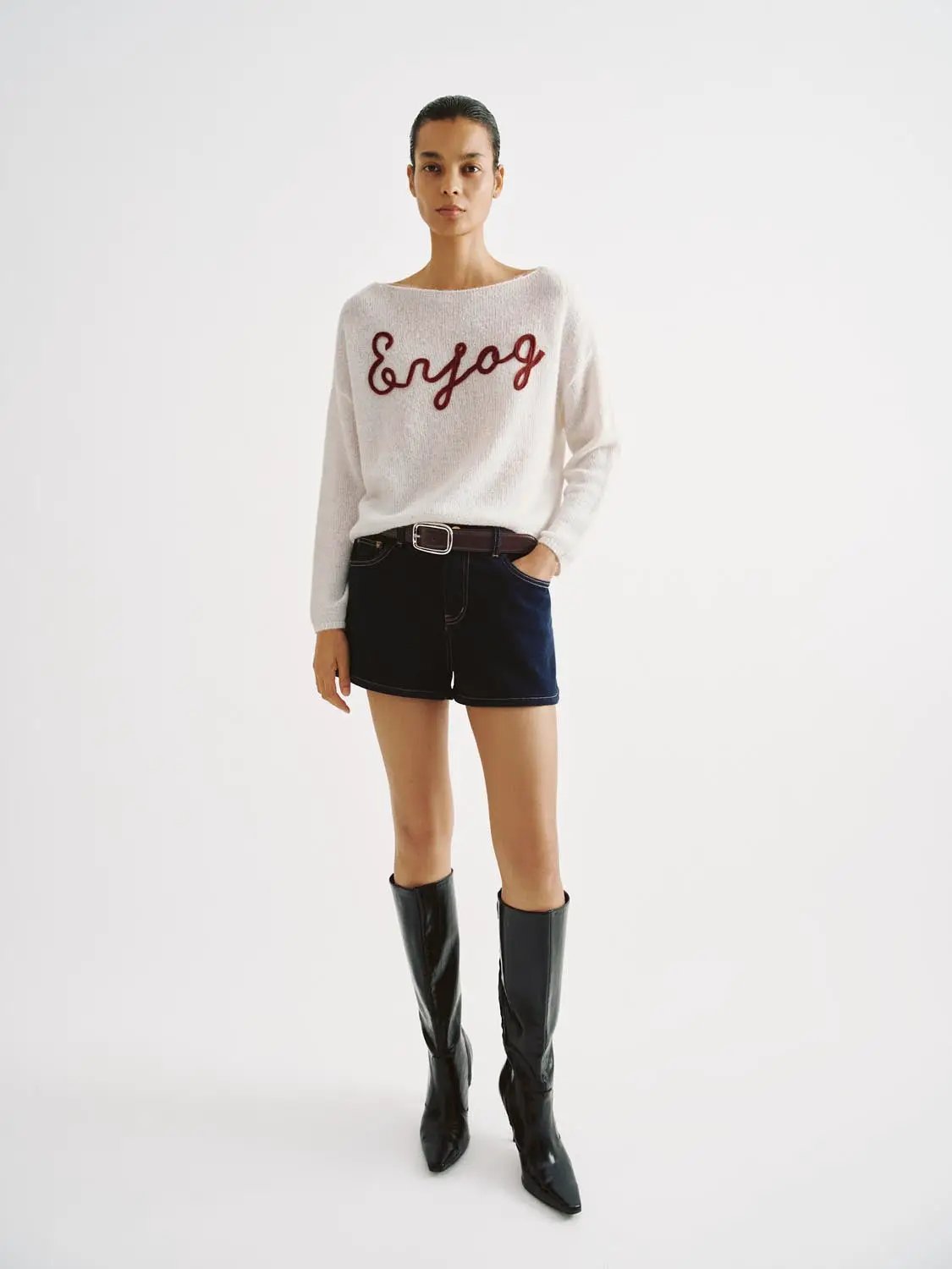 Knit lightweight sweater with red script embroidery, white knit fabric, worn with dark shorts and knee-high boots