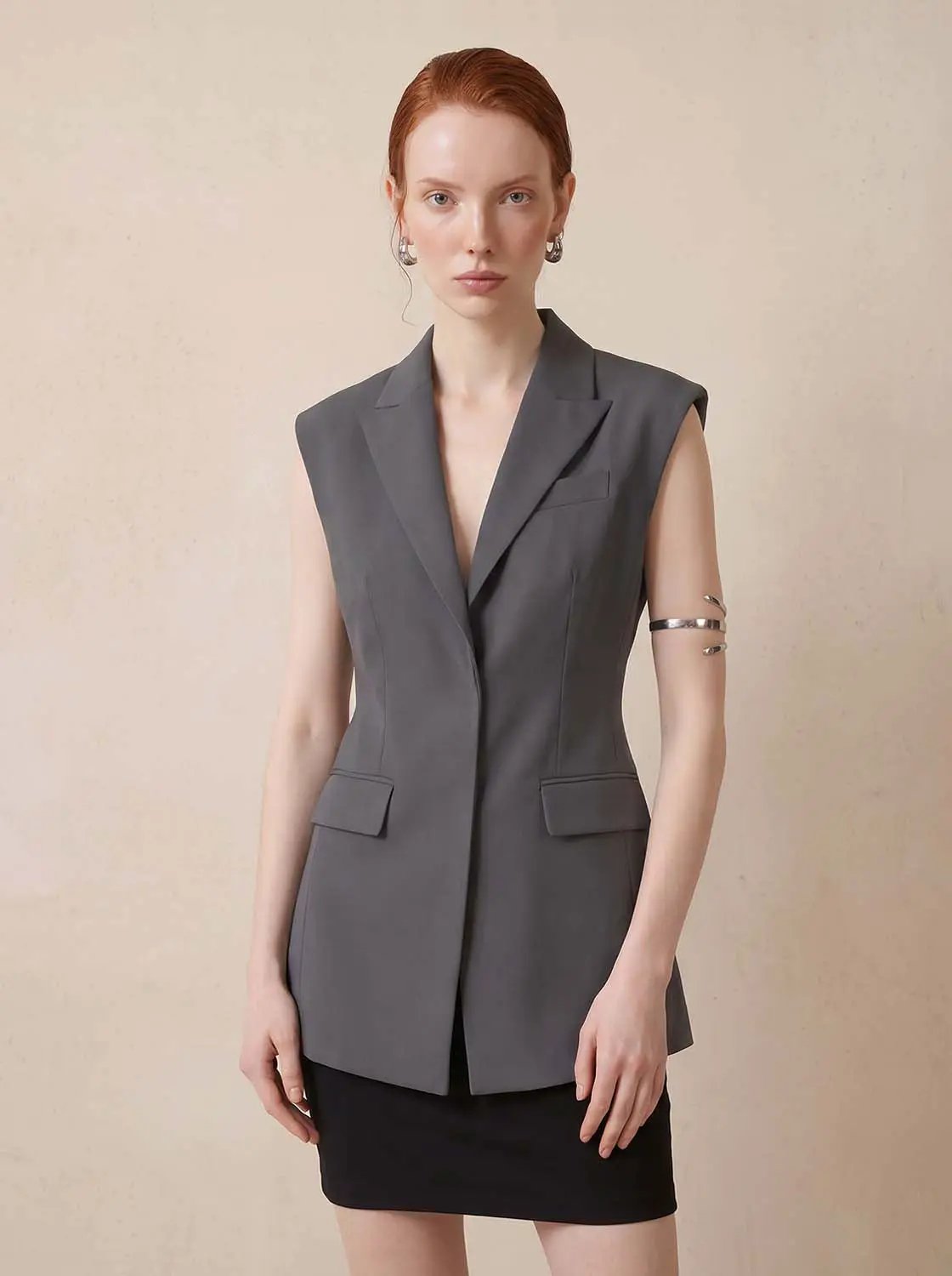 Sleeveless lapel-collar button-front vest in gray with front flap pockets.