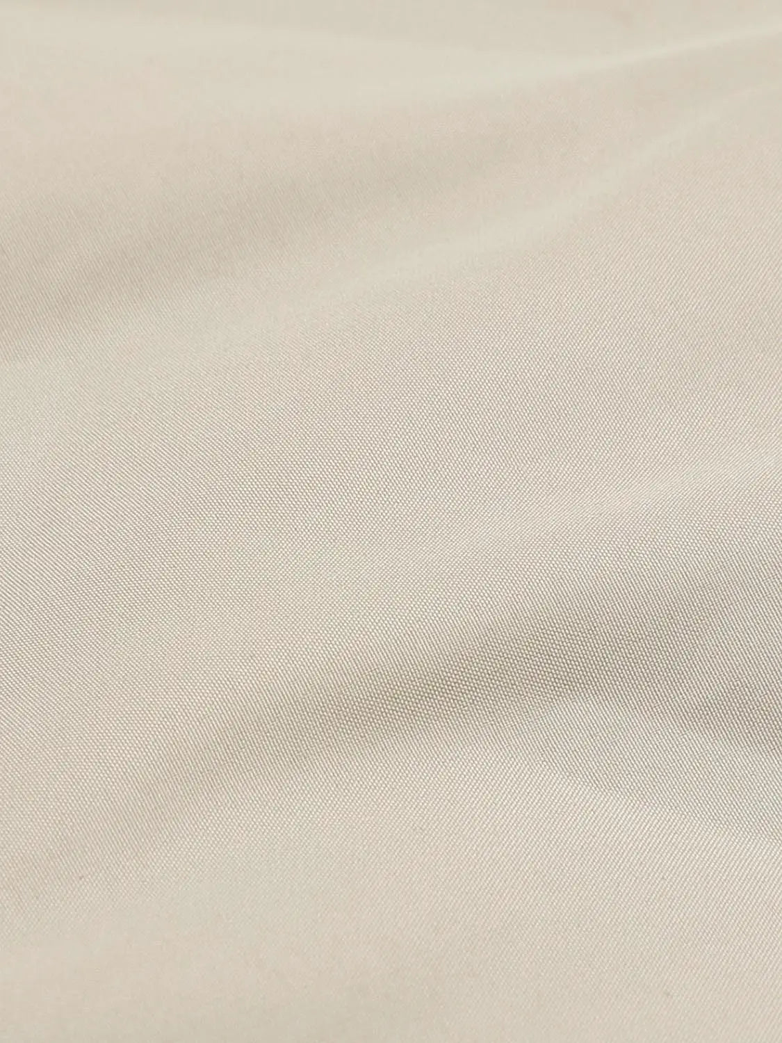 Down jacket beige fabric close-up with fine diagonal weave.