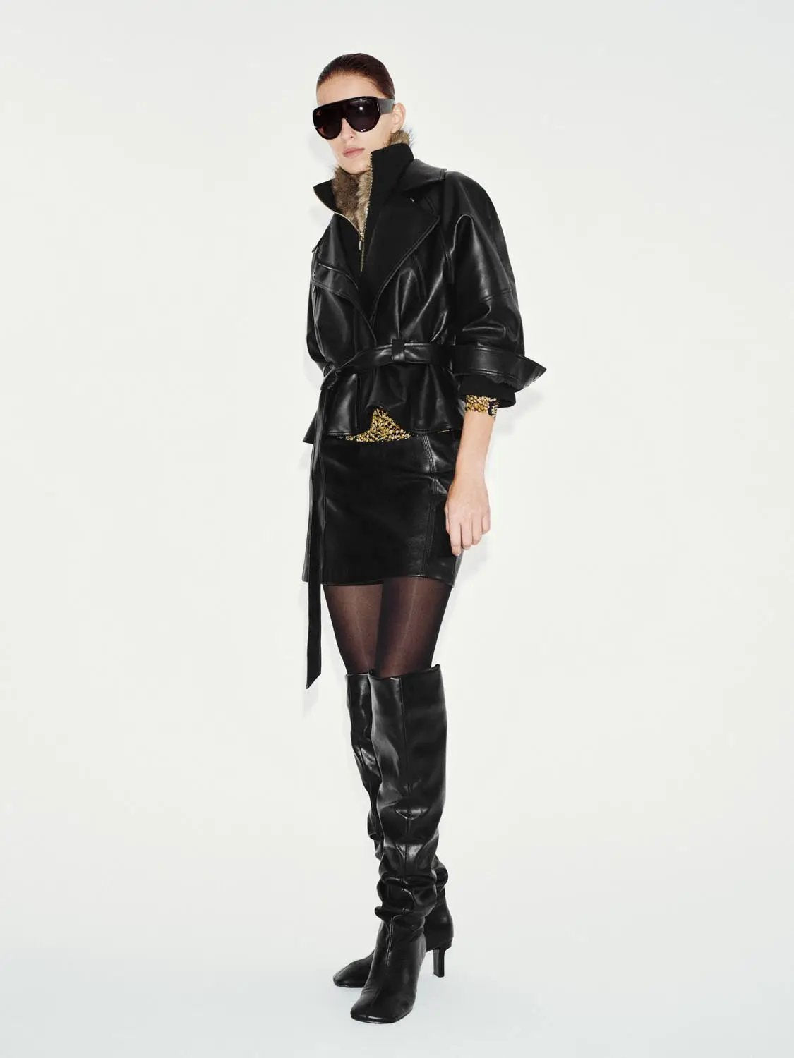 Jacket Urban Revivo Fashion black leather belted with fur collar, worn with knee-high boots.