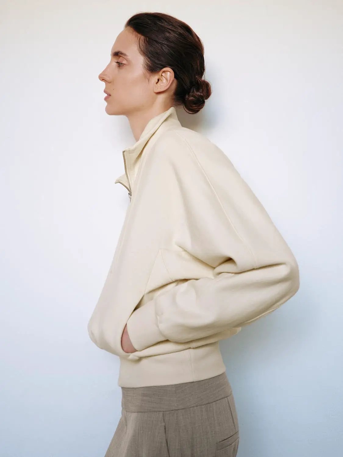 Sweatshirt in cream color with zip-up neckline, shown in side profile.