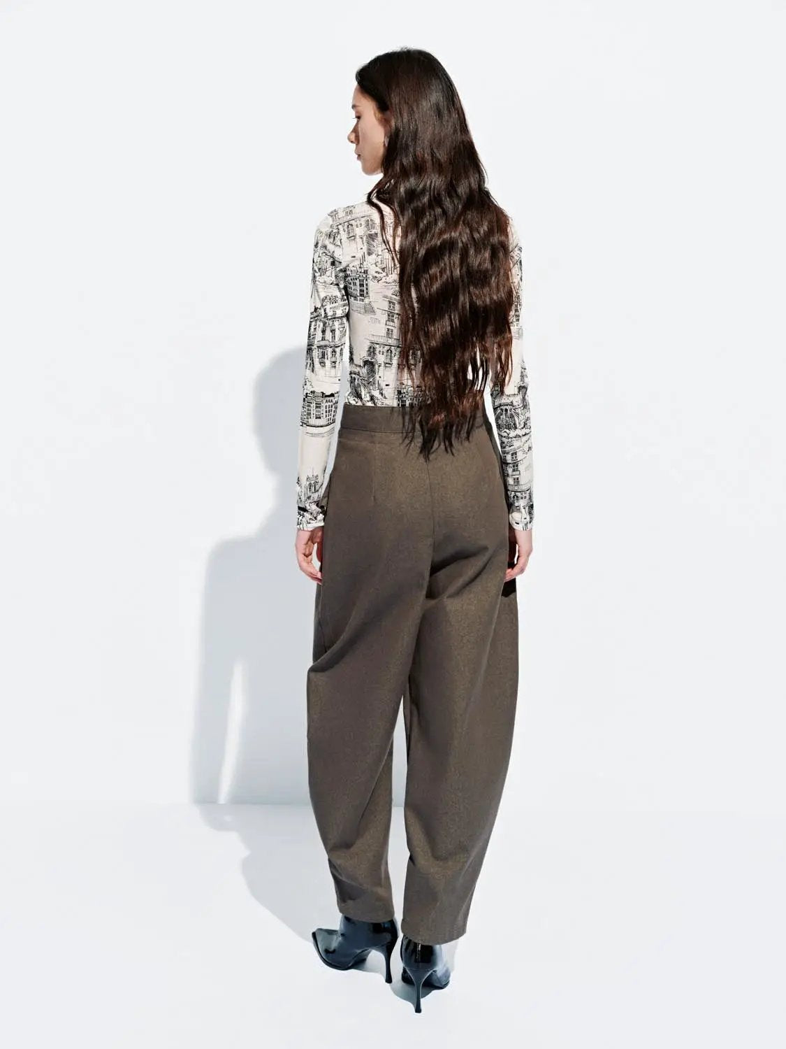Layered Overlay Draped Waist Wide-Leg Cotton Trousers in olive brown; high-waist style paired with a city-print long-sleeve top.