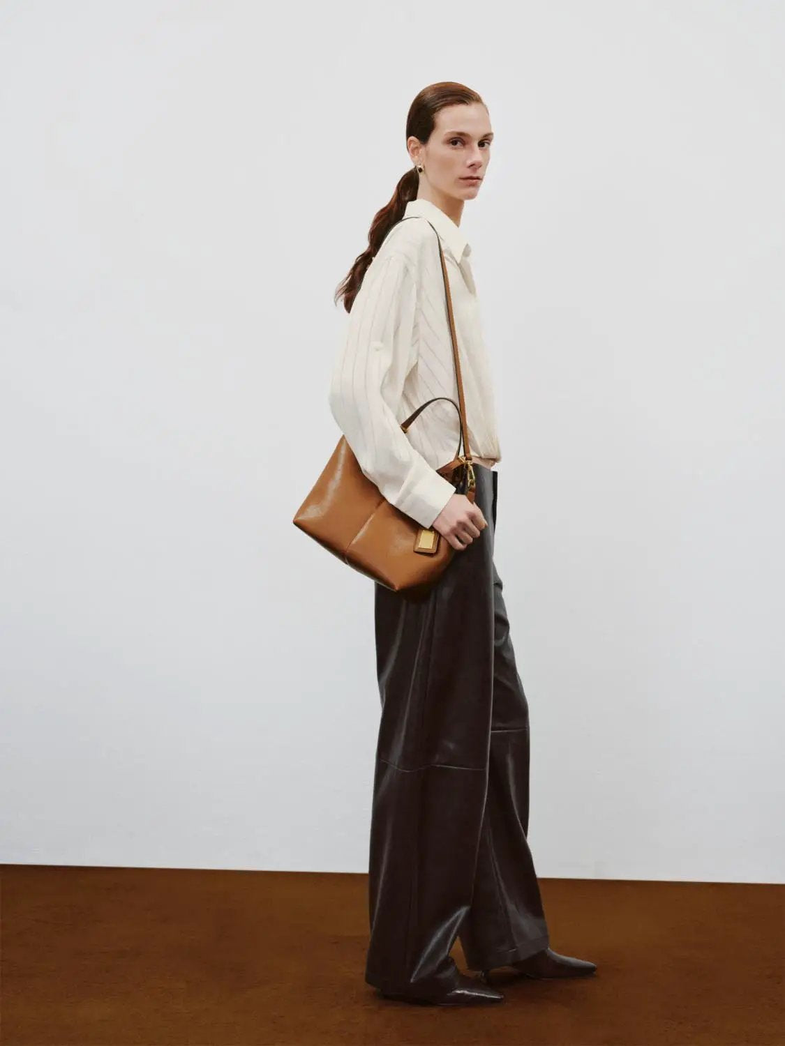 Mid-rise curved-leg faux leather pants in dark brown by Urban Revivo Fashion