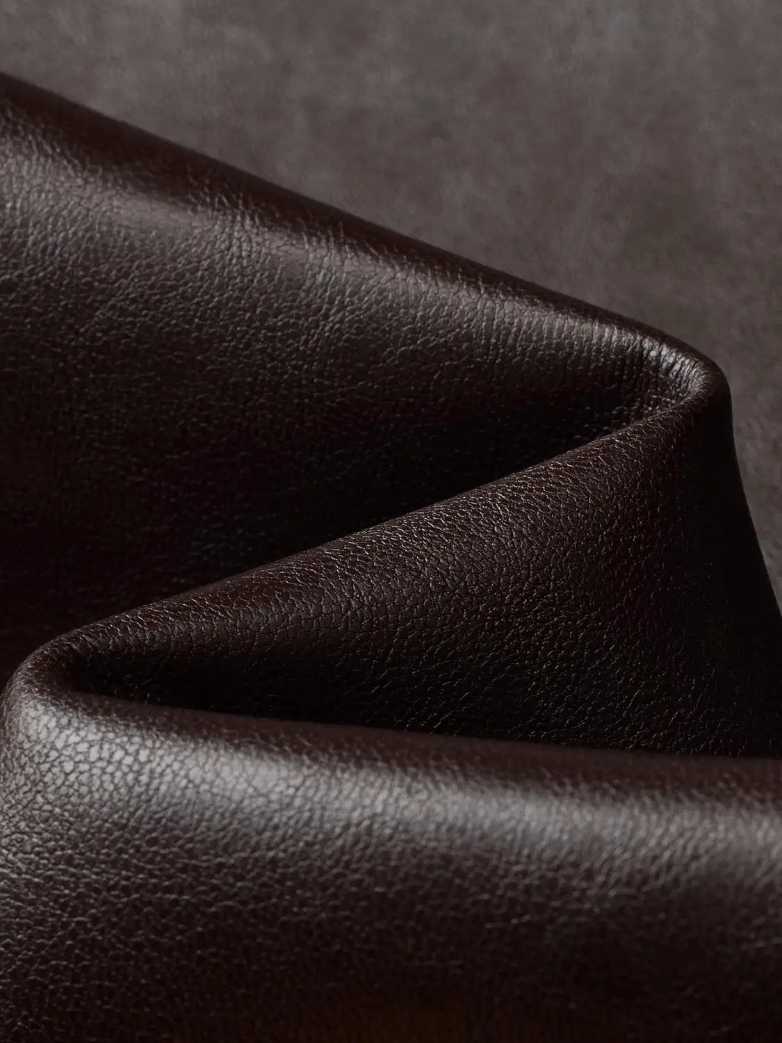 Mid-rise curved-leg faux leather pants; black textured leather-like fabric close-up
