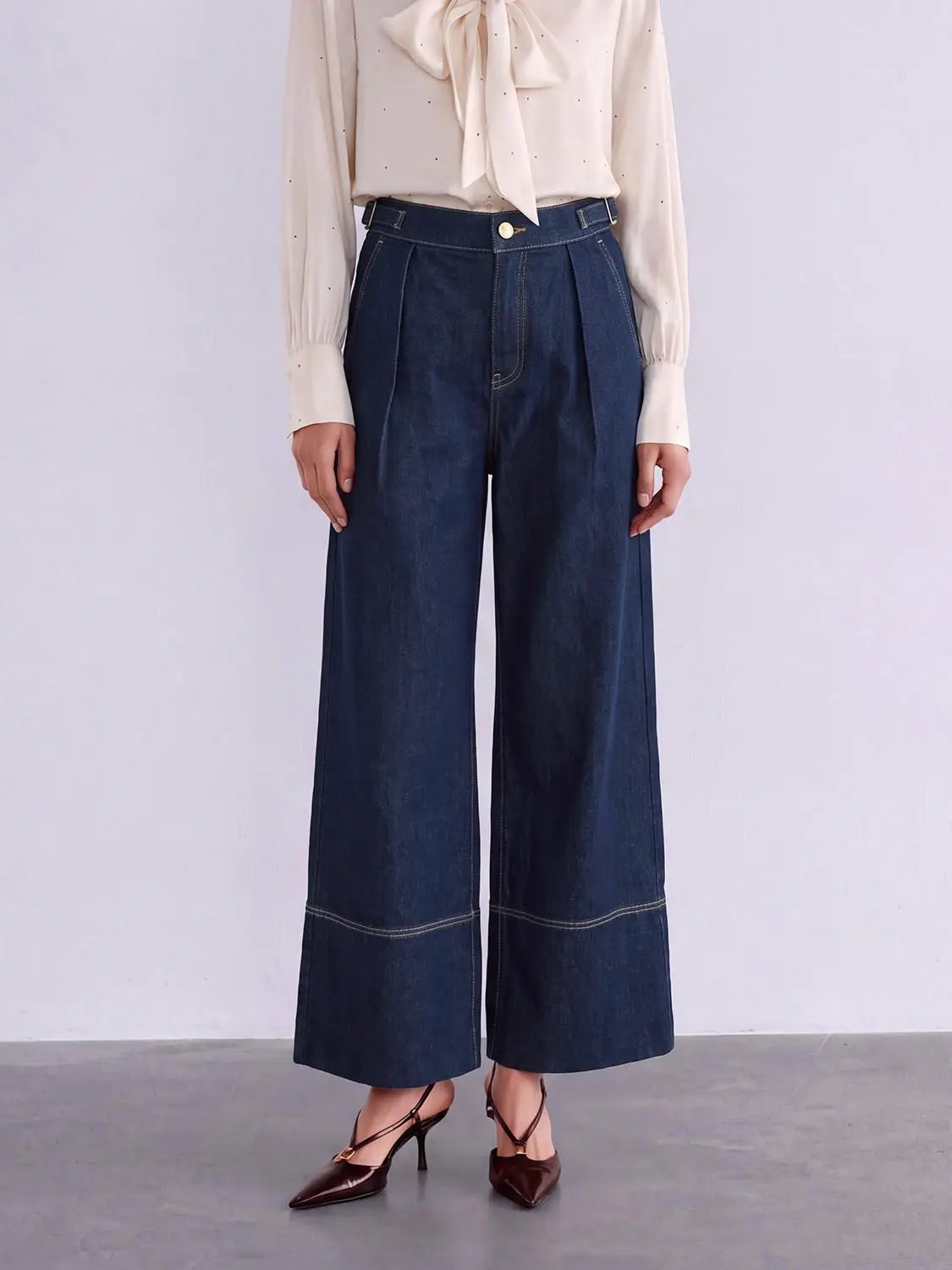 Jeans, dark indigo wide-leg denim with high waist, front pleats, and gold button.