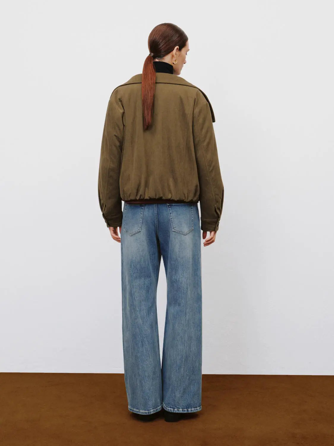 Jeans, blue wide-leg denim, back view of model wearing an olive bomber jacket