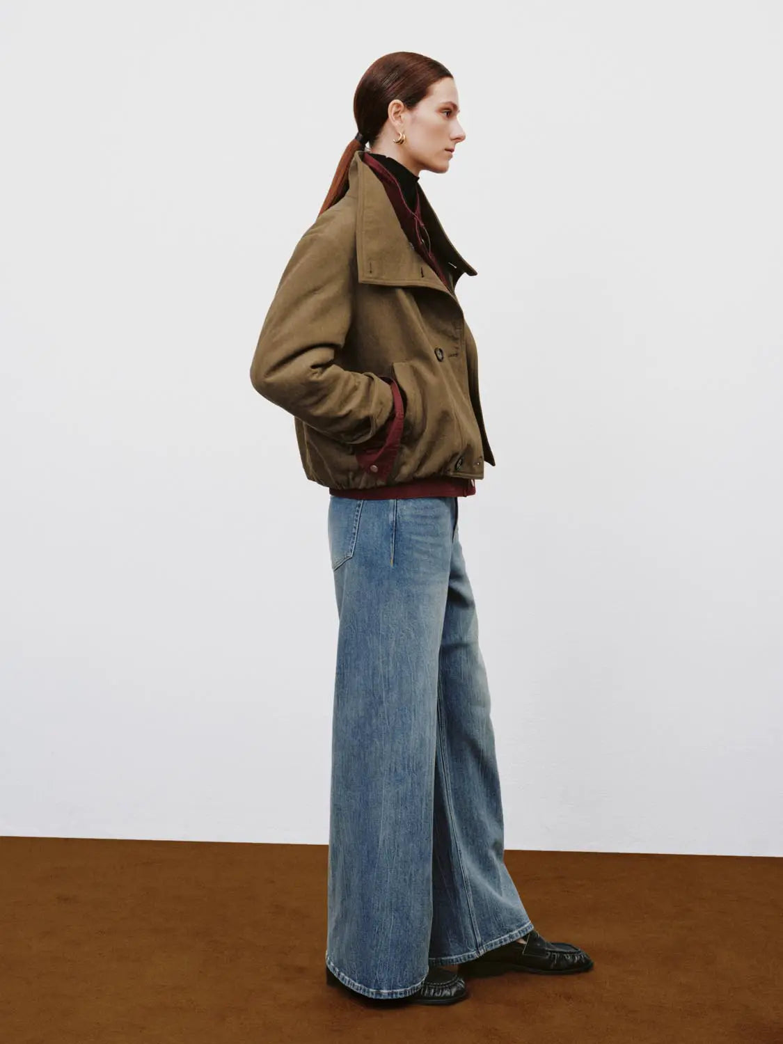 Jeans in light blue denim with a wide-leg silhouette, shown with a brown jacket.